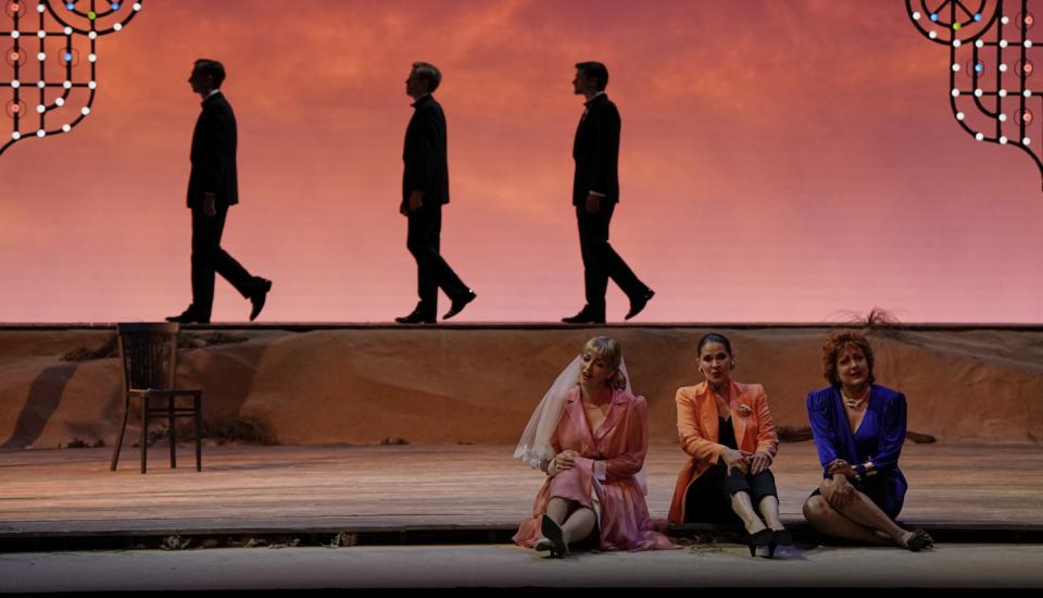 Trois femmes assises au premier plan, trois hommes marchant vers la gauche au second