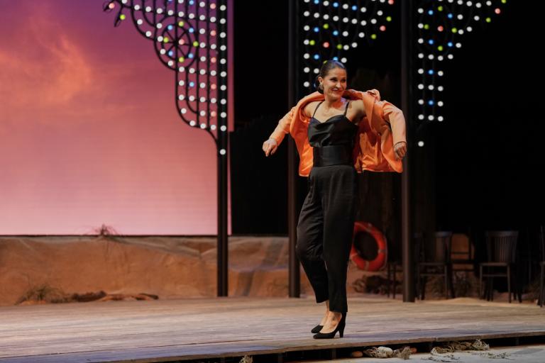 Une femme dansant, remettant sa veste rose sur sa tenue noire